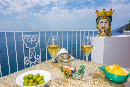 stół z dwoma kieliszkami wina i talerzem owoców w obiekcie Villa Pietra Santa w mieście Positano