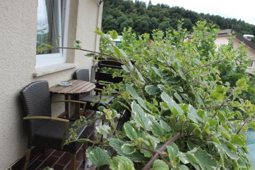 a balcony with a table and chairs and plants at PONI NAKLO - Sobe Marinšek in Naklo