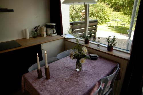 a table with two candles and a vase with flowers on it at Henne Strand Ferie Accommodation in Hennebjerg