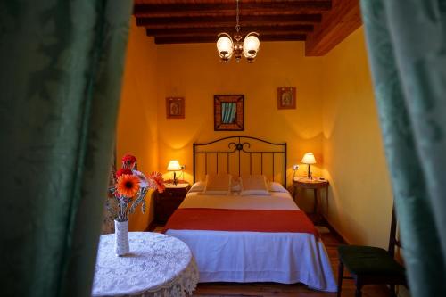 Un dormitorio con una cama y un jarrón de flores sobre una mesa. en Casa Maricuelo, en Castropol