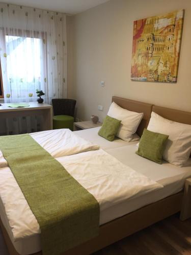 Schlafzimmer mit einem großen Bett mit grüner und weißer Bettwäsche in der Unterkunft Gasthaus Wollscheid in Trier