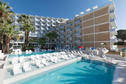 un hotel con piscina, sillas y un edificio en Reverence Mare Hotel - Adults Only en Palmanova