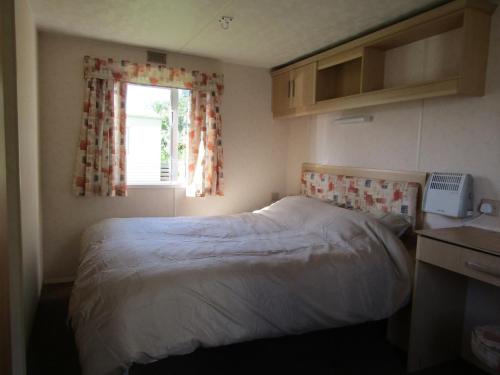 a small bedroom with a bed and a window at Fenlake holiday accommodation in Metheringham
