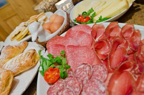 una mesa cubierta con diferentes tipos de carne y pan en Hotel Al Viel B&B en Canazei