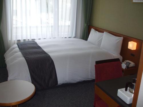a hotel room with a large white bed with a window at Kyoto Garden Palace in Kyoto