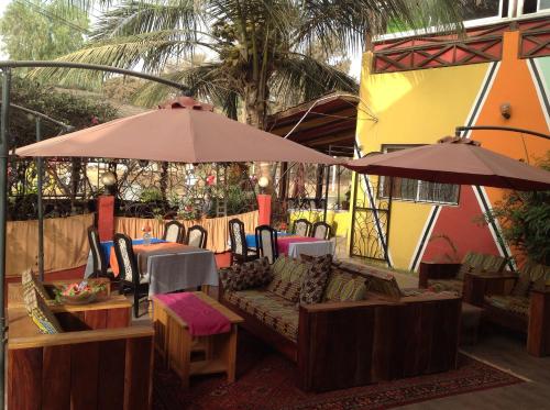 an outdoor patio with tables and chairs and umbrellas at Calabash Apartment-Hotel in Kotu