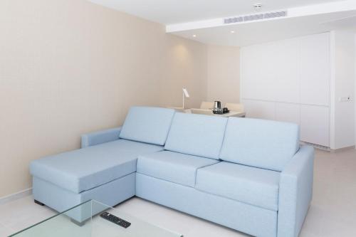 a living room with a blue couch and a table at Reverence Mare Hotel - Adults Only in Palmanova