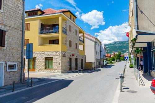 un bâtiment jaune sur le côté d'une rue dans l'établissement Apartments Keli, à Kaštela