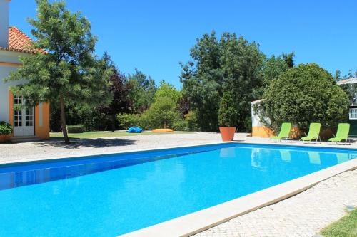 a swimming pool with chairs and a house at Quinta do Casal de Santo António in Alenquer
