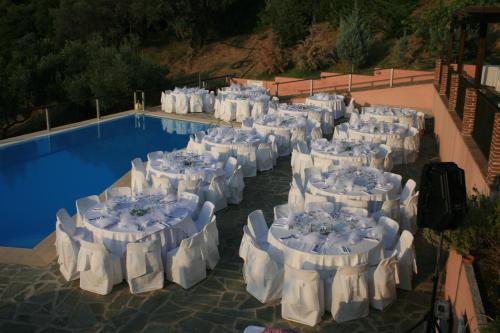 un grupo de mesas con sillas blancas junto a una piscina en Vateri, en Límni
