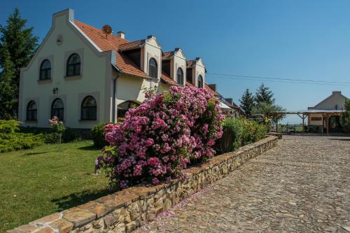 uma casa com flores cor-de-rosa em frente a uma parede de pedra em Garden Vendégház Makó em Makó