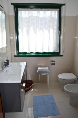 ein Bad mit einem Waschbecken, einem WC und einem Fenster in der Unterkunft BRIONE47 in Riva del Garda