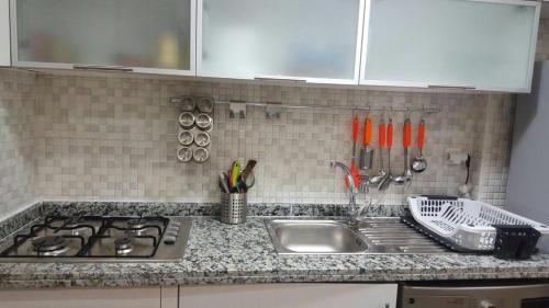 a kitchen counter with a sink and utensils at Résidence Bab Sebta in Fnidek