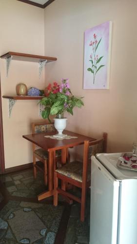 a kitchen with a table with a vase of flowers on it at Pousada das Palmeiras in Camanducaia