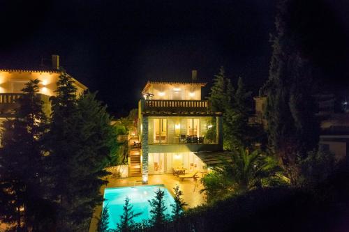 a large house with a swimming pool at night at Porto Heli Villa in Porto Heli