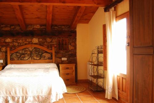 ein Schlafzimmer mit einem Bett und einer Steinwand in der Unterkunft Casa rural LA LAGUNA in Laguna del Marquesado