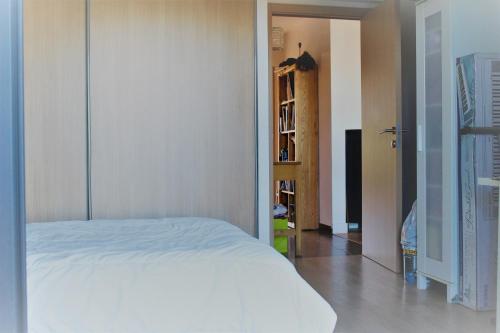 - une chambre avec un lit blanc et une étagère dans l'établissement Appartement de Louise proche aéroport, à Lucciana