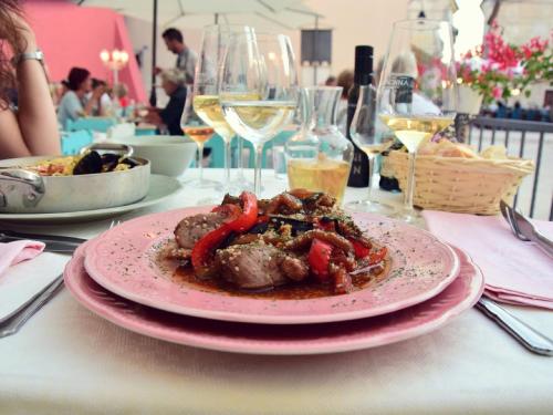 a plate of food on a table with wine glasses at Heritage Hotel Chersin in Fažana