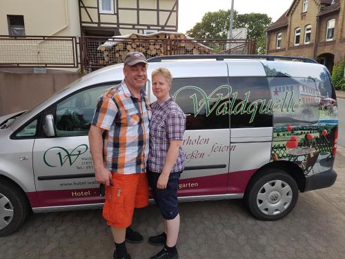 a man and a woman standing in front of a van at Hotel Waldquelle - Baumhaushotel Aerzen in Aerzen