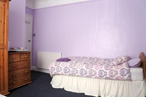 a bedroom with a bed and a purple wall at Smugglers Rest in Newquay
