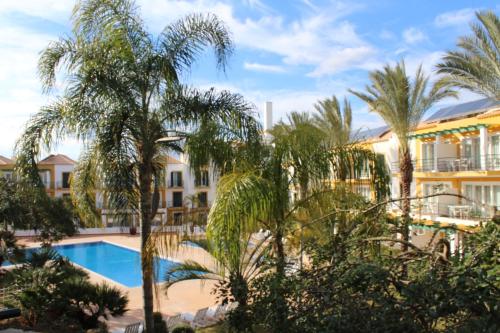 a view of a resort with a pool and palm trees at Charming Monte da Eira- one bedroom in Tavira