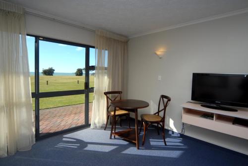 sala de estar con mesa, sillas y TV en Harbour View Seaside Accommodation Napier, en Napier