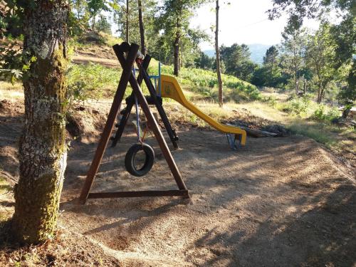a playground with a slide next to a tree at Casas de Canavezes in Marco de Canaveses