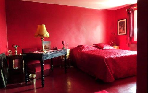 - une chambre rouge avec un lit et une table avec une lampe dans l'établissement La Dame Au Balcon, à Roussillon