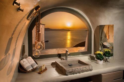 een badkamer met een wastafel en uitzicht op de oceaan bij Aperto Suites - Adults Only in Fira