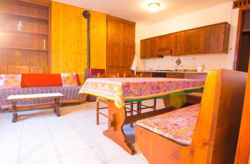 una cocina con armarios de madera, mesa y bancos en Pergolato alpino p.terra, en Teglio
