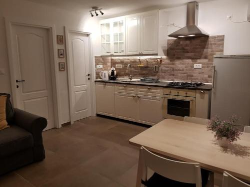 a kitchen with white cabinets and a table and a couch at Sea-esta 2 in Valun