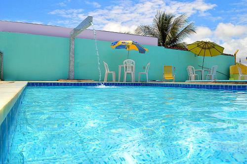 uma grande piscina com cadeiras e um guarda-sol em Pousada Refúgio do Forte em Itamaracá