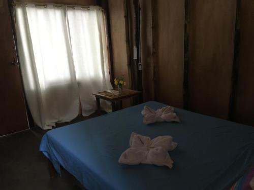a bedroom with a blue bed with towels on it at Prince John Beachfront Eco Bungalows and Restaurant in San Vicente
