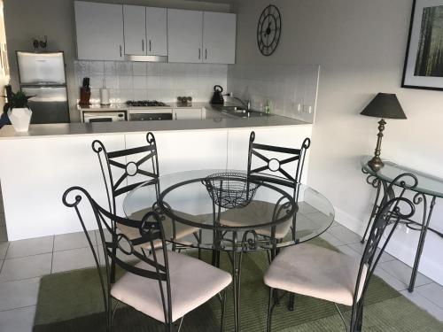 uma cozinha com uma mesa de vidro e 4 cadeiras em Travers Street Apartment em Wagga Wagga