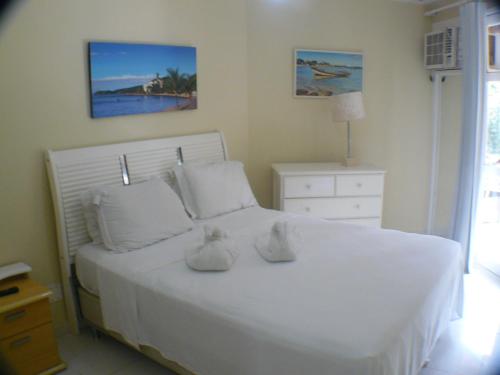 um quarto com uma cama branca com dois sapatos em Buzios Beach Internacional Residence Service em Búzios