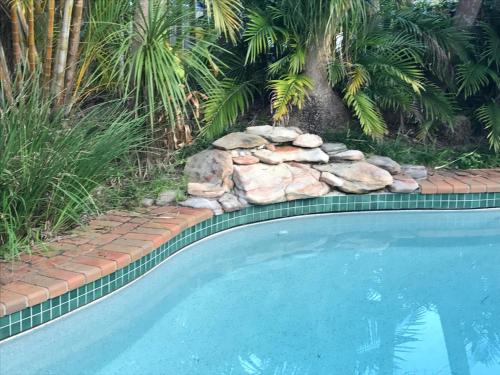 a swimming pool with rocks next to a yard at Guest House on Hyde in Bellingen