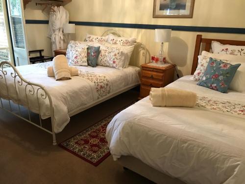 a bedroom with two beds and a table with a lamp at Guest House on Hyde in Bellingen