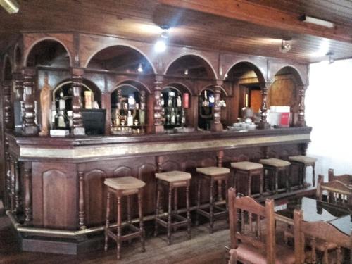 Hotel y Restaurant Don Quijote في Macachín: وجود بار في المطعم مع الكراسي وقوارير الكحول
