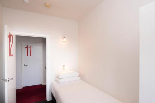 a bedroom with white walls and a bed with white sheets at Mowbray Hotel in Launceston