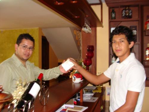 a man is handing a man a bottle of wine at Hostal La Molienda in Puyo