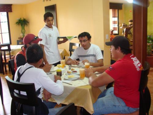 a group of men sitting around a table eating at Hostal La Molienda in Puyo