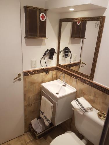 a bathroom with a sink and a toilet and a mirror at Casa 24 Puerto Iguazu in Puerto Iguazú