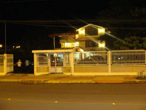 a white fence in front of a house with lights at Hostal La Molienda in Puyo