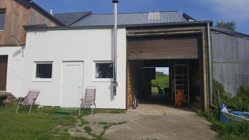 a white building with two chairs and a garage at Gîte BELLA in Ebly
