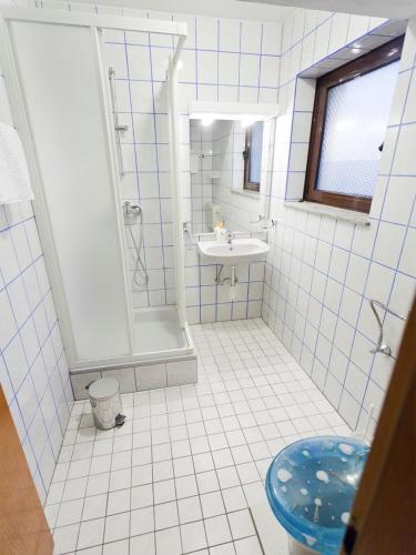 a white tiled bathroom with a shower and a sink at Villa Raljević in Stanići