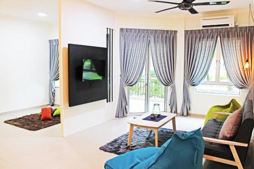 a living room with a couch and a tv at Tiara Desaru Seaview Residence in Desaru