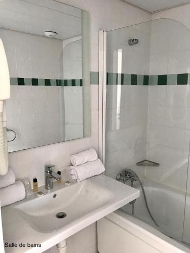 a white bathroom with a sink and a bath tub at Hotel Club Le Plein Sud Vacances Bleues in Hyères
