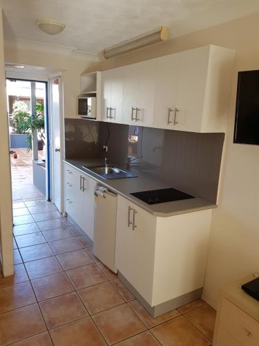 een keuken met witte kasten en een tegelvloer bij Byron Beach House in Byron Bay