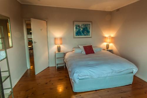 a bedroom with a large bed with two lamps at Antechamber Bay Retreats in Penneshaw