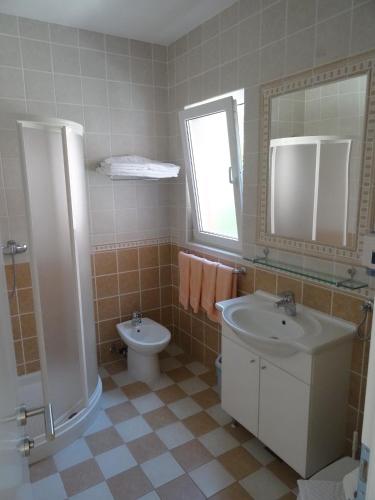 a bathroom with a sink and a toilet and a mirror at Neva Apartments in Šimuni